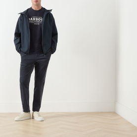 Model wearing Barbour navy casual jacket with hood, styled with matching navy logo sweatshirt, dark trousers and white trainers.
