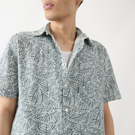 Model wearing Barbour Derham Patch Pocket Printed Shirt in Dusty Slate, short-sleeved linen-cotton blend with all-over leaf print and chest patch