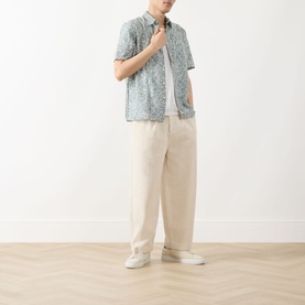 Model wearing Barbour Derham Patch Pocket Printed Shirt in Dusty Slate, styled with cream wide-leg trousers and white trainers.