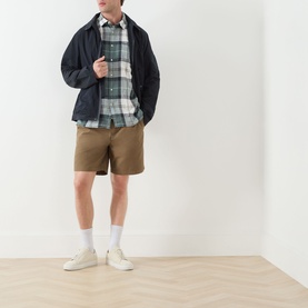 Model wearing Barbour Meadow Brook Tartan casual shirt in green check linen blend, styled with navy jacket, tan shorts and white trainers.