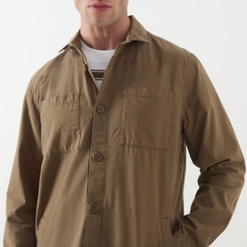 Model wearing khaki button-front overshirt with chest pockets, styled over a striped white and navy crew-neck tee