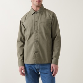 Model wearing Barbour casual shirt in Dusty Olive, featuring chest pocket and button-front fastening, styled with blue jeans.