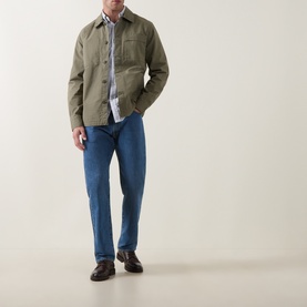 Model wearing Barbour Dusty Olive cotton casual shirt jacket with chest pockets, styled with blue jeans and dark loafers.