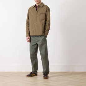 Model wearing Barbour Strick Flap Pocket Overshirt in Clay, styled with olive trousers and brown suede trainers.