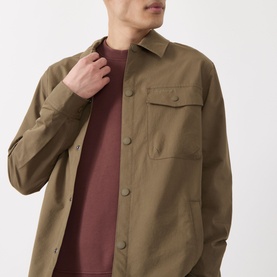 Model wearing Barbour Strick Flap Pocket Overshirt in Clay, with chest flap pocket and snap buttons, styled over a burgundy crew-neck tee.