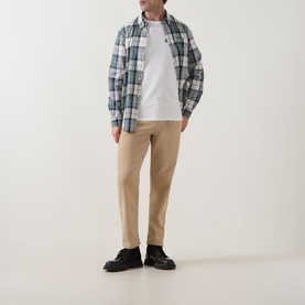 Model wearing Barbour Whisper White Crew Neck T-shirt, styled with blue check overshirt, beige chinos and black shoes.