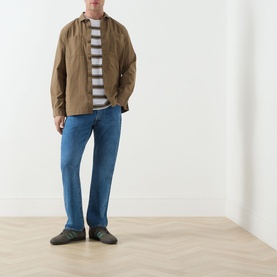 Model wearing Barbour White Crew Neck T-Shirt, styled with tan overshirt, blue jeans and dark loafers.