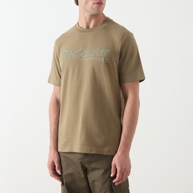 Model wearing Barbour Milburn Graphic Logo T-Shirt in Clay, crew neck with chest logo graphic, styled with khaki cargo trousers