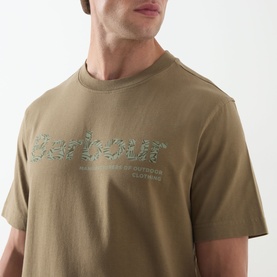 Model wearing Barbour Milburn Graphic Logo T-Shirt in Clay, showing tonal chest graphic detail on crew neck cotton tee.