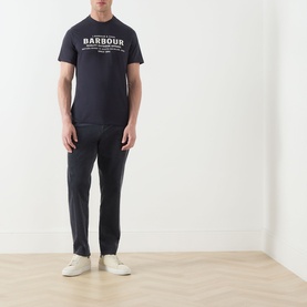 Model wearing Barbour Dark Navy crew neck T-shirt with white chest logo, styled with navy trousers and white trainers.
