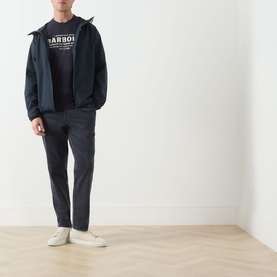 Model wearing Barbour Dark Navy Crew Neck T-shirt, styled with navy zip jacket, charcoal trousers and white trainers.