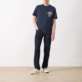 Model wearing Barbour Camping Trip T-Shirt in Navy with Running Heart chest motif, styled with dark jeans and white trainers.