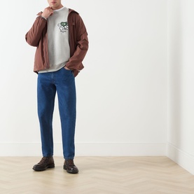 Model wearing Barbour Grey Marl cotton crew neck sweatshirt, styled with brown jacket, blue jeans and dark brown boots.