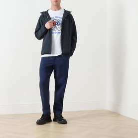 Model wearing Barbour white cotton crew neck T-shirt, styled with navy zip-up jacket, navy trousers and black loafers.