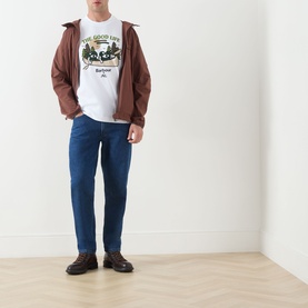 Model wearing a brown zip-up jacket over a white graphic tee, styled with mid-blue straight-leg jeans and dark brown shoes.