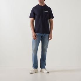 Model wearing Barbour Moonwell Graphic Logo T-Shirt in Dark Navy with light wash straight-leg jeans and white trainers.