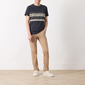 Model wearing Barbour Teeside Graphic Logo T-Shirt in Dark Navy with contrast chest stripes, styled with tan chinos and white trainers.