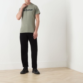 Model wearing sage green Barbour logo T-shirt with black trousers and black trainers