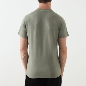Model wearing sage green crew neck short sleeve T-shirt, back view, curved hem