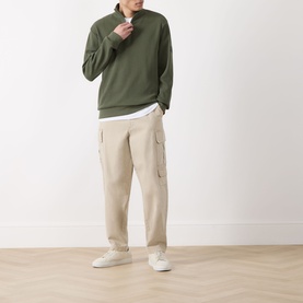 Model wearing Barbour International Thyme half zip cotton sweat with beige cargo trousers and white trainers