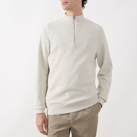 Model wearing Barbour Raven Logo Half-Zip Sweater in Ecru Marl, styled with beige trousers. Half-zip fastening, ribbed trims, logo detail.