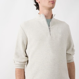 Model wearing Barbour Raven Logo Half-Zip Sweater in Ecru Marl, styled over a sage green crew-neck tee.