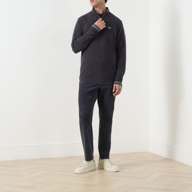 Model wearing Barbour Dark Navy cotton half zip sweatshirt, styled with matching navy trousers and white trainers.