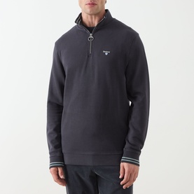 Model wearing Barbour Dark Navy cotton half-zip sweatshirt with striped cuffs and silver zip detail at collar.