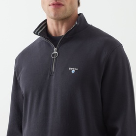 Model wearing Barbour Dark Navy cotton half-zip sweat, silver zip pull, logo embroidery, styled with striped collar detail visible at neck.