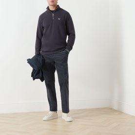 Model wearing Barbour Dark Navy cotton half-zip sweatshirt, styled with navy trousers, white trainers, carrying a navy jacket.