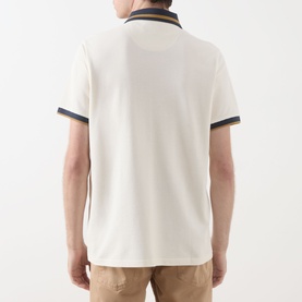 Model wearing Barbour Anthorn Textured Logo Polo Shirt in Whisper White, back view, with navy tipped collar and cuff trims, paired with tan trousers.