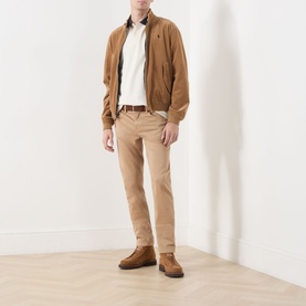 Model wearing Barbour Anthorn Textured Logo Polo Shirt in Whisper White, styled with tan bomber jacket, beige chinos and brown suede boots.