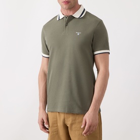 Model wearing Barbour Anthorn Textured Logo Polo Shirt in Dusty Olive with white tipped ribbed collar and cuffs, paired with tan trousers.