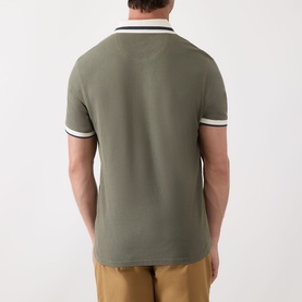 Model wearing Barbour Anthorn Textured Logo Polo Shirt in Dusty Olive, back view, with white and black tipped ribbed collar and cuffs.