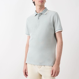 Model wearing Barbour Barnard Logo Polo Shirt in Dusty Slate, with white tipping on collar and cuffs, styled with cream trousers.