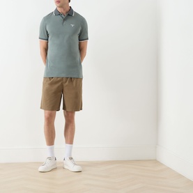 Model wearing Barbour Vintage Teal polo shirt with tipped collar, styled with tan shorts, white socks and trainers.