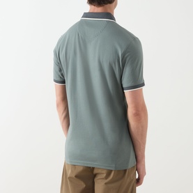 Model wearing Barbour polo in Vintage Teal, rear view, with contrast dark collar and white tipped sleeves, styled with khaki trousers.