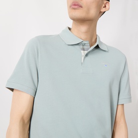 Model wearing Barbour polo shirt in Dusty Slate, short sleeve pique cotton with small logo embroidery and check-lined collar detail.