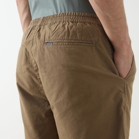 Model wearing Barbour clay cotton shorts, close-up of back pocket with elasticated waistband detail, styled with grey t-shirt.
