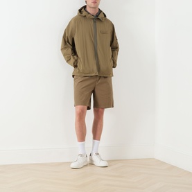 Model wearing Barbour clay cotton shorts, styled with matching hooded jacket, grey tee and white trainers
