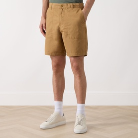 Model wearing Barbour Sherburn Logo Straight-Leg Shorts in Camel, styled with white socks and white low-top trainers.