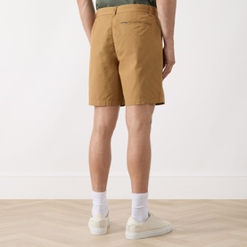 Model wearing Barbour Sherburn Logo Straight-Leg Shorts in Camel, rear view, styled with white trainers and white socks.