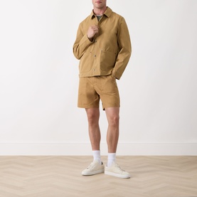 Model wearing Barbour Sherburn Logo Straight-Leg Shorts in Camel with matching jacket and white trainers.