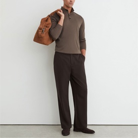 Model wearing Reiss ridge brown half-zip knit jumper with dark trousers, carrying a tan leather holdall bag.