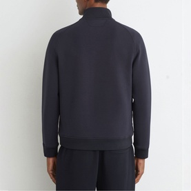 Model wearing Reiss blue zip-neck sweatshirt, back view, styled with matching navy joggers.
