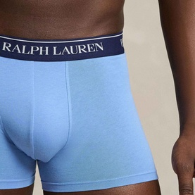 Model wearing Ralph Lauren Classic Stretch Trunk in Bristle Blue with navy logo waistband, part of a 3-pack set.