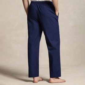 Model wearing navy blue straight-leg cotton trousers with elasticated waist, shown from behind, barefoot
