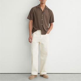Model wearing Reiss taupe brown short-sleeve checked shirt with cream wide-leg trousers and beige suede loafers.