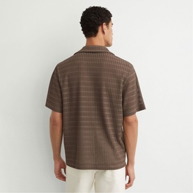 Model wearing Reiss taupe brown short-sleeve camp collar shirt with textured stripe pattern, styled with cream trousers, back view.