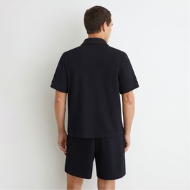 Model wearing Reiss blue short-sleeve shirt, back view, styled with matching blue shorts